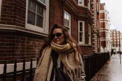 Portrait of woman standing against building