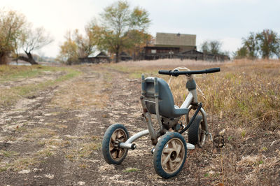 Old children's tricycle on a country road in the autumn.