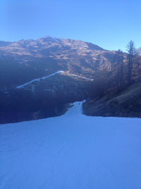 Scenic view of snow covered mountains against clear blue sky