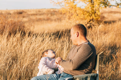 Autumn warm embrace, a young dad and his daughter find joy in a field of gold