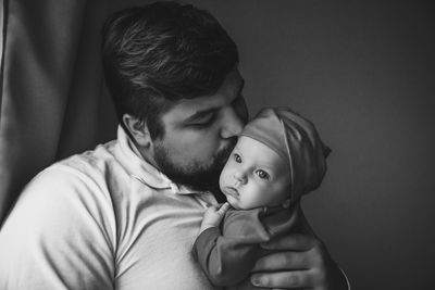 Father kissing baby girl against wall