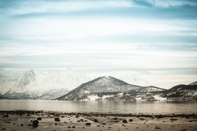 Scenic view of lake by snowcapped mountains against sky