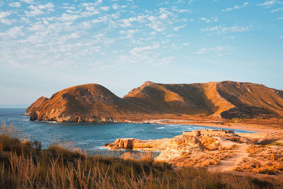 Scenic view of rocks by sea against sky