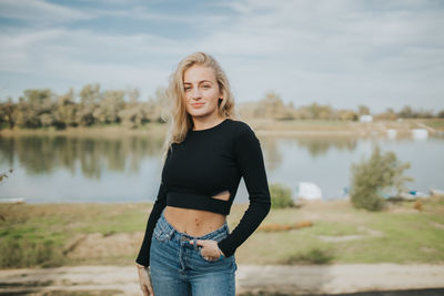 Portrait of smiling young woman standing near water