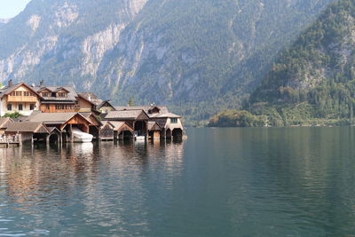 Houses by lake and buildings against mountains