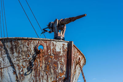 Low angle view of abandoned ship against clear blue sky