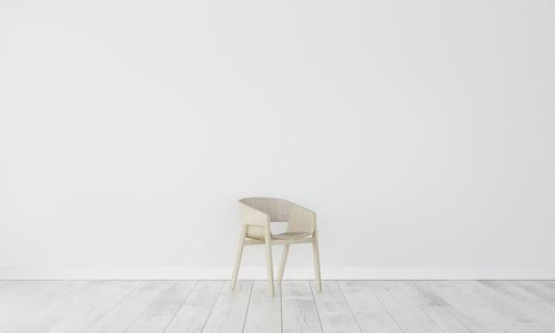 Empty chair against white wall