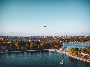 Hot air balloons flying over river and buildings in city 