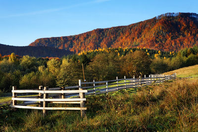 Scenic view of wooden fence against mountains in autumn