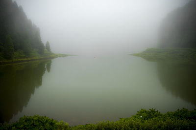 Scenic view of calm lake in foggy weather
