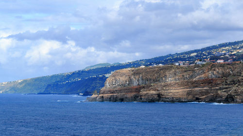 Scenic view of sea and mountains against cloudy sky