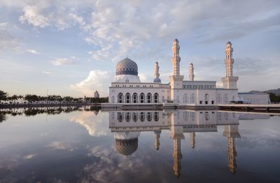 Reflection of church in lake against cloudy sky