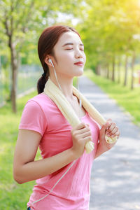 Woman listening music while standing on footpath