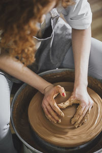 High angle view of female potter molding clay in workshop