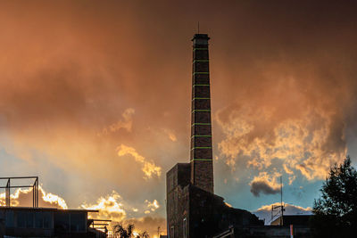 Low angle view of an old restored brick chimney against the sky during sunset