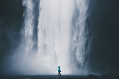 Woman walking against skogafoss