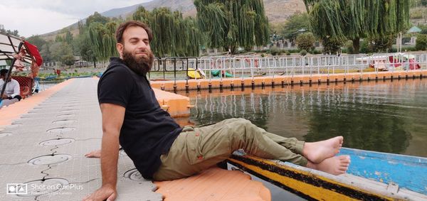 Young man sitting by lake