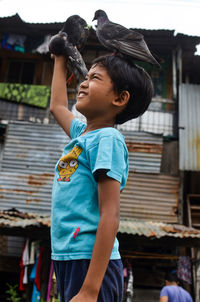 Boy looking away while standing against built structure