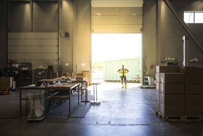 Full length of senior warehouse worker standing at storage room doorway