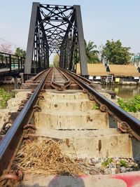 Railroad tracks by bridge against sky