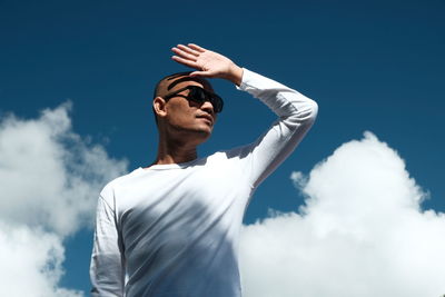Low angle view of man standing against blue sky on a sunny day