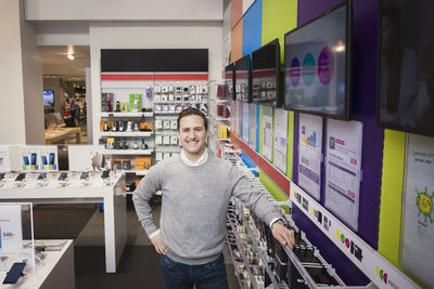 Portrait of cheerful salesman standing in electronics store