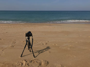 Full length of photographer on beach against sky