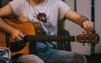 Midsection of man playing guitar