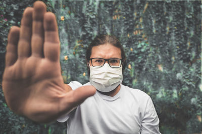 Portrait of man wearing mask gesturing stop sign