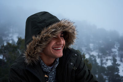 Latin young man smiles in a coat on a snowy day