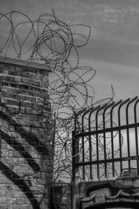 Low angle view of barbed wire fence against sky