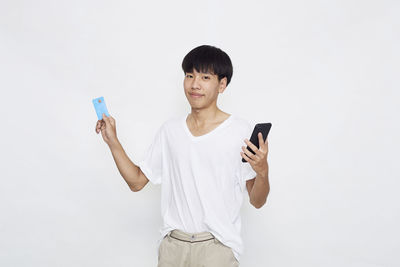 Young man using mobile phone against white background