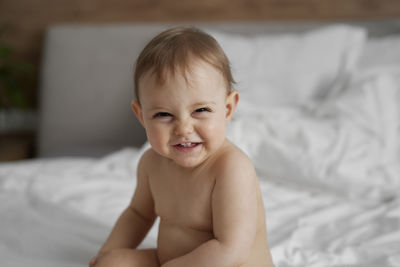 Close-up of cute baby boy lying on bed at home