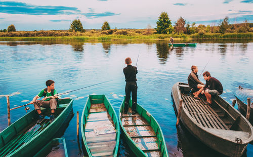 People on boat in lake against sky