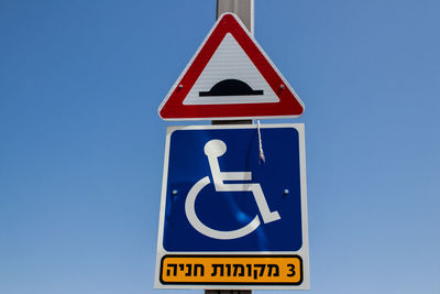 Low angle view of road sign against clear blue sky