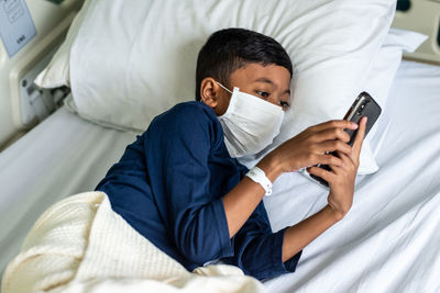 Rear view of boy lying on bed