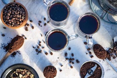 Still life with glass mugs of black hot coffee, coffee beans, making coffee at home