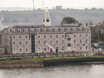 Buildings by river against sky