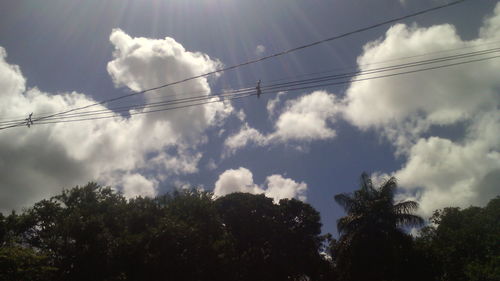 Low angle view of power lines against cloudy sky