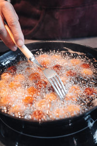 Close-up of person preparing food in cooking pan