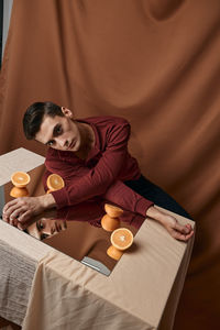 Portrait of man on mirror with orange against colored background