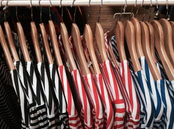 High angle view of striped patterned t-shirts hanging on coathangers at store