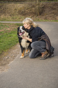 Woman with dog crouching on road