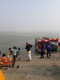 People at beach against clear sky