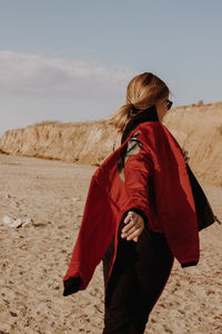 Side view of woman holding jacket against mountain and sky