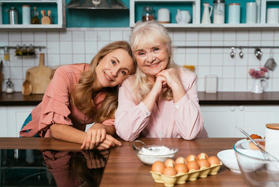 Portrait of smiling mother and daughter at kitchen