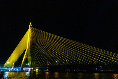 Illuminated bridge over river against sky at night