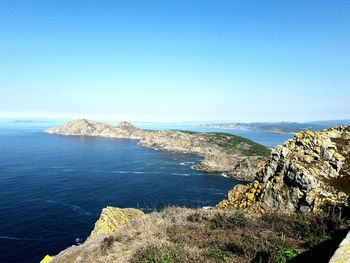 Scenic view of sea and mountains against clear blue sky