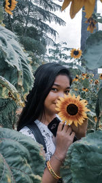 Portrait of smiling woman holding flowering plant