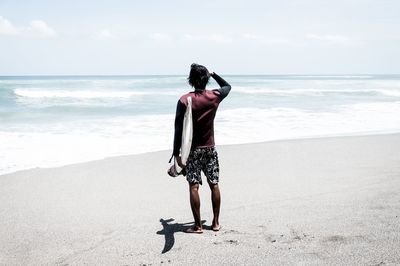 Rear view of woman standing on beach against sky